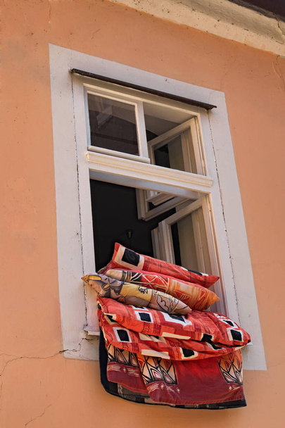 Kirkkaan keltainen oranssi seinä maalaismainen vanha talo, jossa on avoin ikkuna ja tyynyt ja huopa. Loket, Tsekin tasavalta
. - Valokuva, kuva