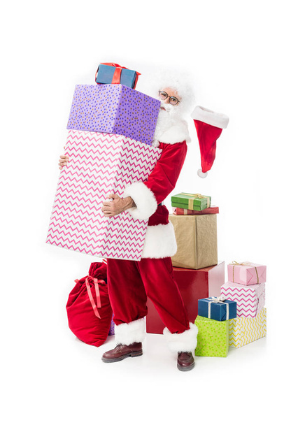 Weihnachtsmann in Brille mit Stapel von Geschenkschachteln auf weißem Hintergrund  - Foto, Bild
