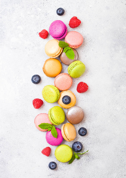 Dessert cake macaron or macaroon with raspberry and blueberry on stone kitchen background . Top view.  - Foto, imagen