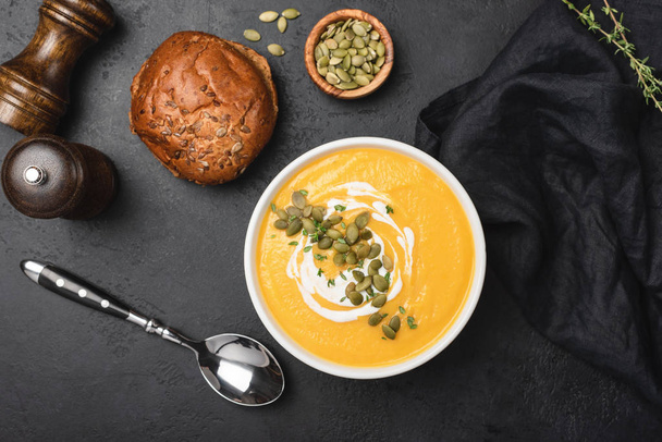 Tasty pumpkin cream soup in bowl over black background - Valokuva, kuva