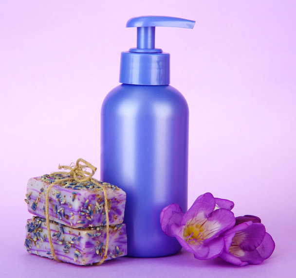 Liquid and hand-made soaps on purple background - Фото, изображение