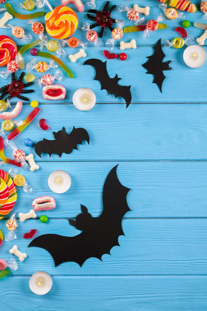 Assorted teeth and eyeball shaped candy spread on wooden table, jelly spider, gummy worms, round lollipop and other mixed candy on blue wood background. Top view, copy space, close up, flat lay. - Foto, afbeelding
