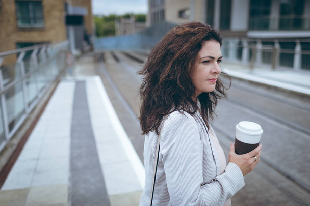junge Geschäftsfrau mit Kaffeetasse steht am Bahnhof - Foto, Bild