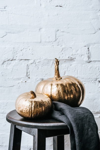 close-up shot of two halloween pumpkins painted in golden metallic in front of white brick wall - Foto, Imagem