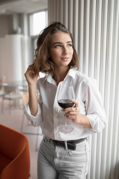 Cute woman holding red wine glass standing in the restaurant - Valokuva, kuva