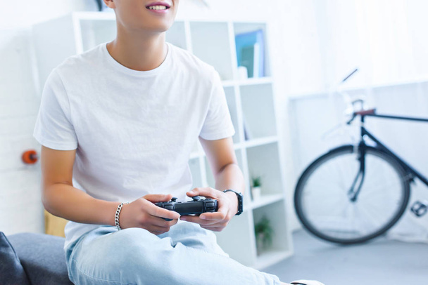 image recadrée d'un homme souriant jouant à un jeu vidéo sur un canapé à la maison
 - Photo, image