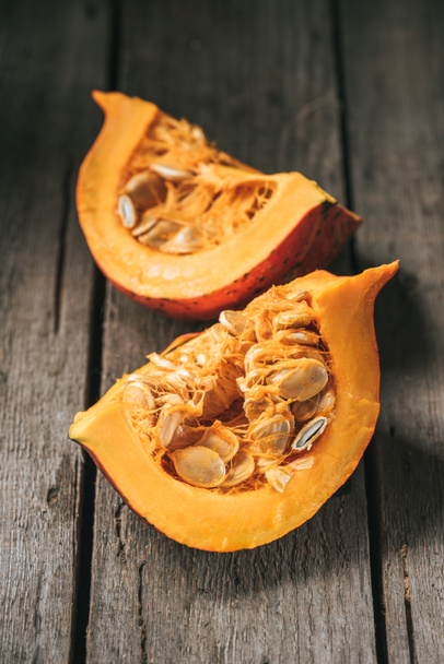 Close up view of raw pumpkin halves on wooden background - 写真・画像