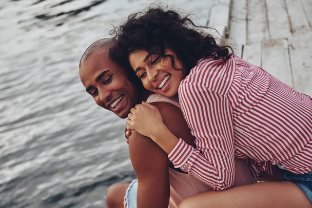 romantic couple sitting on pier at lake and hugging  - Φωτογραφία, εικόνα