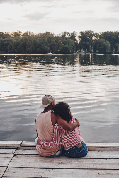 Achteraanzicht van romantische paar zittend op de pier in lake  - Foto, afbeelding