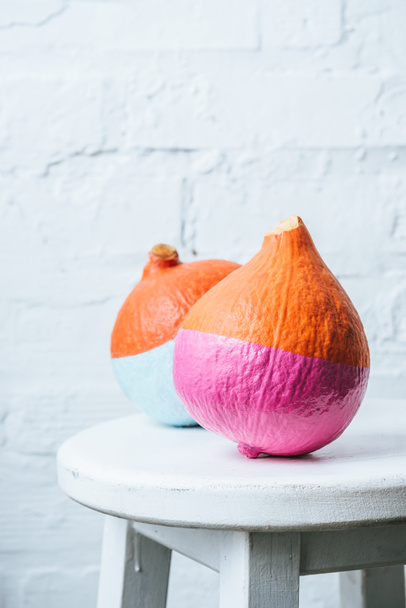 close up view of colored in pink and blue pumpkins on white brick wall backdrop - 写真・画像