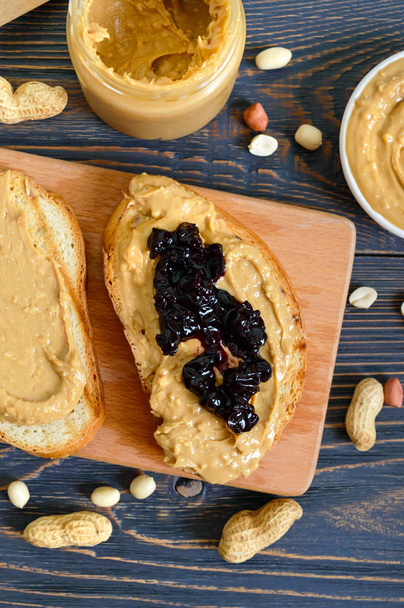 Crispy toast with peanut butter and berry jam. Traditional American breakfast. - Zdjęcie, obraz