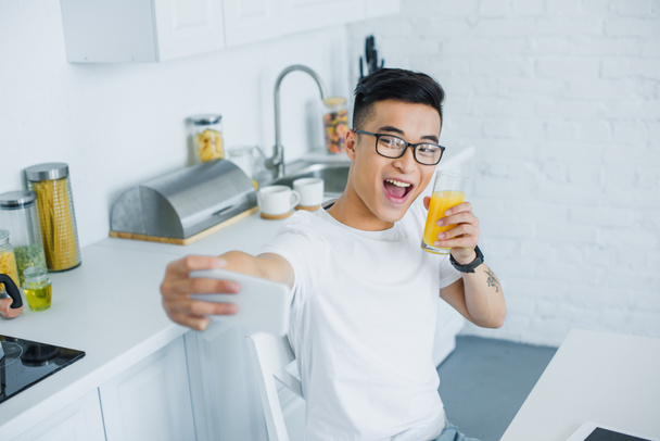 happy young man drinking juice and taking selfie with smartphone - Photo, image
