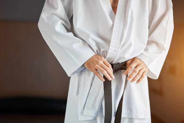 Hands tightening black belt on man dressed in kimono - Fotografie, Obrázek