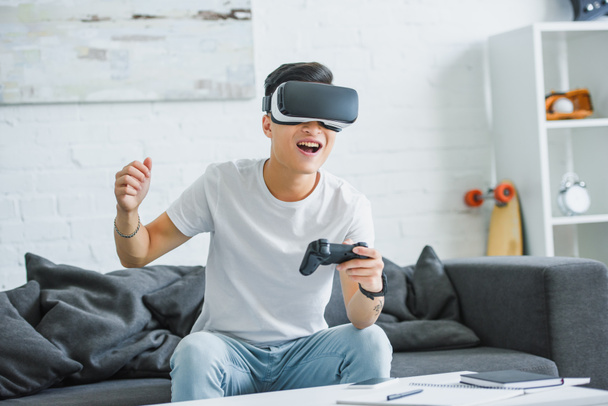 自宅のジョイスティックで遊ぶ仮想現実のヘッドセットで幸せな若い男 - 写真・画像
