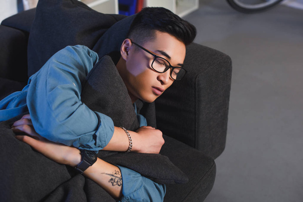 high angle view of young asian man in eyeglasses sleeping on sofa at home  - Фото, зображення
