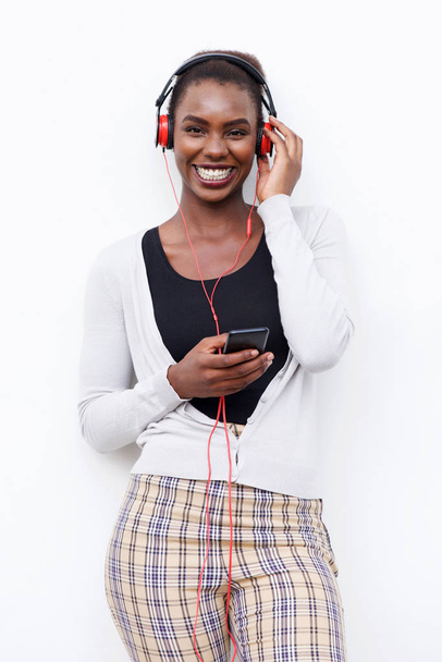 Portrait of happy black woman with headphones and mobile phone against white background - Photo, Image