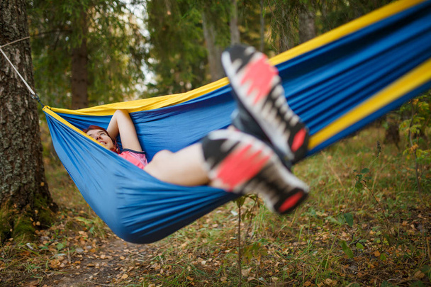 Image of young brunette lying in hammock in woods - Valokuva, kuva