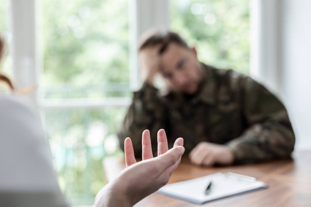 Close-up on therapist hand while helping depressed soldier during treatment - Foto, Imagen
