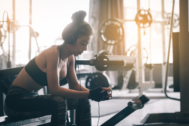 Femme asiatique de détente et d'exercice avec écouter de la musique après l'entraînement à la salle de gym
. - Photo, image