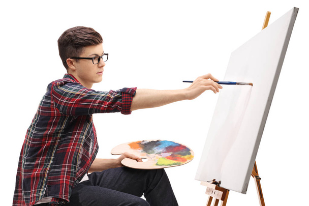 Teenage boy painting on a canvas isolated on white background - Photo, image