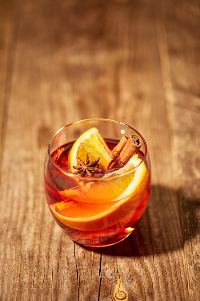 close up view of hot mulled wine drink with orange pieces and anise stars on wooden tabletop - Zdjęcie, obraz