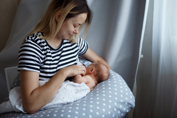 Een jonge moeder is borstvoeding haar zeven-dag-oude dochter. Close-up. Het concept van natuurlijke voeding, gezond eten. - Foto, afbeelding