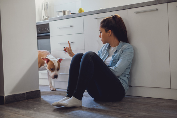 Fille gronder son chien assis sur le sol de la cuisine
 - Photo, image