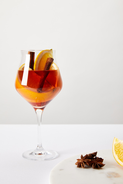 close up view of tasty mulled wine with orange pieces and anise stars on white tabletop on grey background - Photo, Image