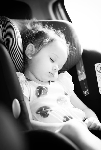 Ładny blond dziecko śpiące w dziecięcego fotelika samochodowego. Koncepcja bezpieczeństwa. - Zdjęcie, obraz