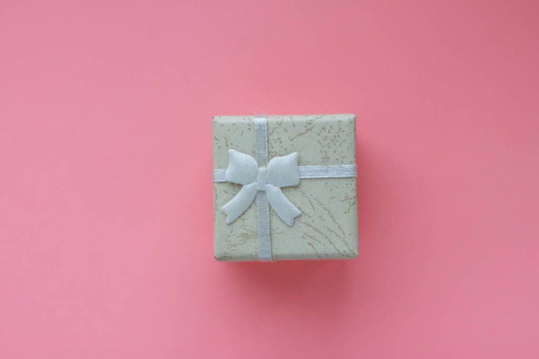 pequeña caja de regalo con cinta sobre fondo rosa
  - Foto, imagen