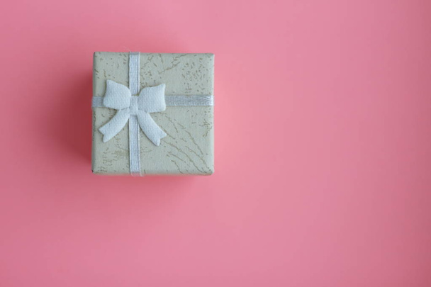 pequeña caja de regalo con cinta sobre fondo rosa
  - Foto, imagen