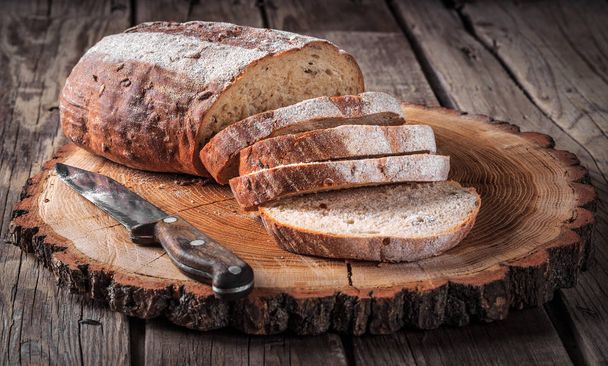 Dilimlenmiş ekmek ve ahşap kesme tahtası üzerinde bıçak. Ahşap rustik arka plan - Fotoğraf, Görsel