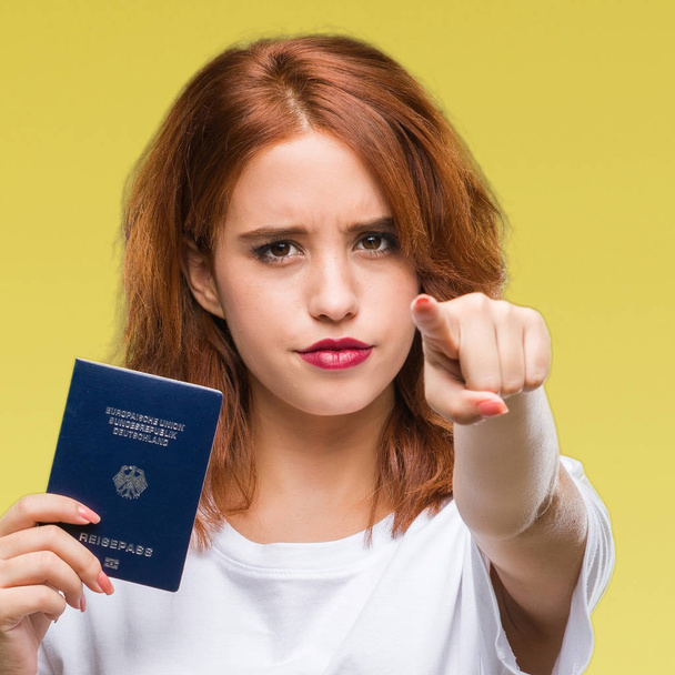 Nuori kaunis nainen, jolla on Saksan passi eristetyn taustan yli osoittaen sormella kameraa ja sinua, käsimerkki, positiivinen ja luottavainen ele edestä
 - Valokuva, kuva