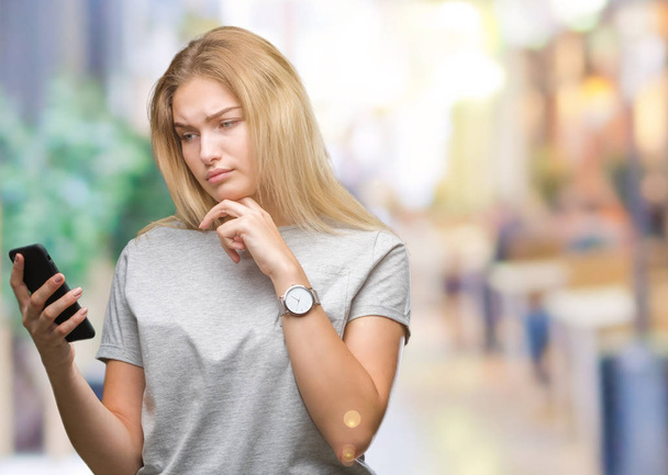 Νεαρή γυναίκα Καυκάσιος στέλνοντας μήνυμα χρησιμοποιώντας smartphone πέρα από το απομονωμένο φόντο σοβαρό πρόσωπο σκέψης σχετικά με την ερώτηση, πολύ συγκεχυμένη ιδέα - Φωτογραφία, εικόνα