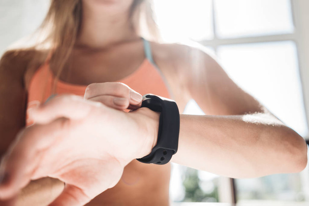 Fitness woman after workout session checks results on smartwatch in fitness app. Healthy lifestyle concept. Female athlete wearing sport tracker wristband arm - Φωτογραφία, εικόνα