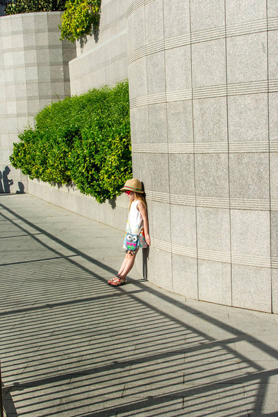 Little girl stands against the wall and looks at the shadow - 写真・画像