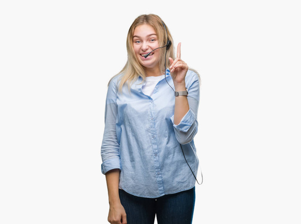Młody biznes kaukaski kobieta noszenia call center zestaw słuchawkowy na białym tle wskazując palcem udany pomysł. Wyszedł i szczęśliwy. Numer jeden. - Zdjęcie, obraz