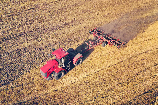 Levegőkép drón aratási területen traktor nyírja a száraz füvet. Őszi sárga mező szénakazalban betakarítás után felülnézetből. Aratás a földeken. Raktározd fel a szénát télre. Felülnézet. - Fotó, kép