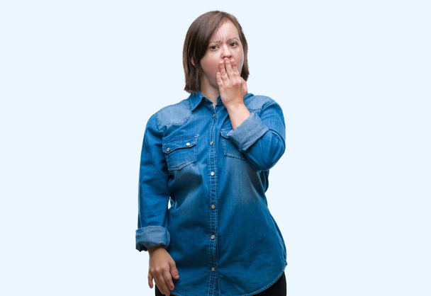 Mujer adulta joven con síndrome de Down sobre fondo aislado aburrido bostezo cansado cubriendo la boca con la mano. Inquietud y somnolencia
. - Foto, imagen