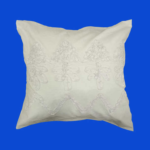 Декоративная подушка с узором из розовых нитей, вышитой. Изолированный на синем фоне
. - Фото, изображение