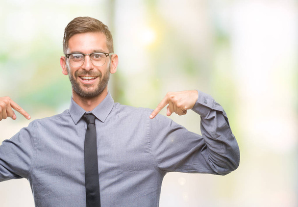 Young handsome business man over isolated background looking confident with smile on face, pointing oneself with fingers proud and happy. - Photo, Image