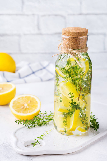 Health care, fitness, healthy nutrition diet concept. Fresh cool lemon thyme infused water, cocktail, detox drink, lemonade in a glass jar for spring summer days. Light kitchen background - Photo, Image