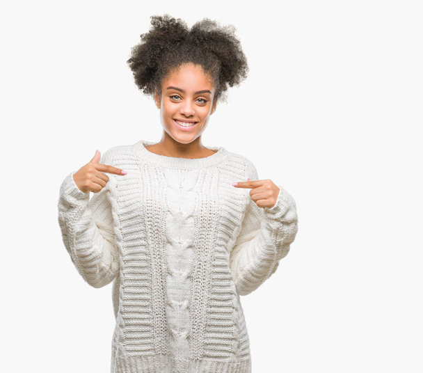Молодая афро-американка в зимнем свитере на изолированном фоне выглядит уверенно с улыбкой на лице, указывая на себя пальцами гордой и счастливой
. - Фото, изображение