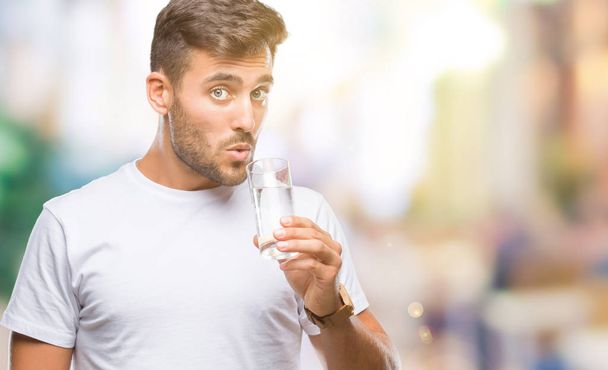 Genç yakışıklı adam akıllı yüzünde ciddi düşünme emin bir ifade ile izole arka plan üzerinde bardak su içme - Fotoğraf, Görsel