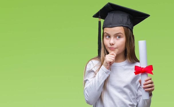 Молодая красивая девушка носит диплом выпускника держа степень на изолированном фоне серьезное лицо, думая о вопросе, очень запутанная идея
 - Фото, изображение