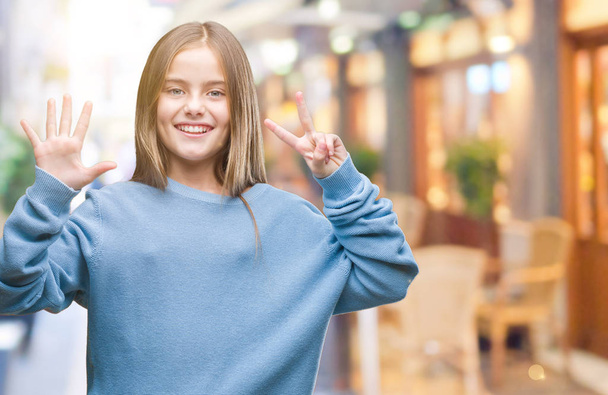 Fiatal gyönyörű lány visel téli pulóver felső elszigetelt háttér bemutatás és ujjal felfelé mutató szám hét, miközben mosolyogva, magabiztos és boldog. - Fotó, kép