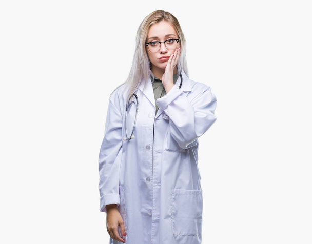 Young blonde doctor woman over isolated background thinking looking tired and bored with depression problems with crossed arms. - Foto, imagen