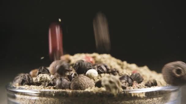Slow motion een mengsel van peper erwten valt in de close-up van zwarte peper - Video