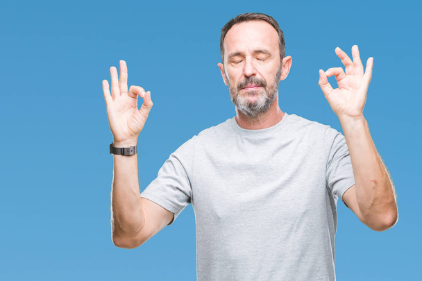 Senior hoary man van middelbare leeftijd op geïsoleerde achtergrond ontspannen en lachend met ogen gesloten doen meditatie gebaar met vingers. Yoga concept. - Foto, afbeelding