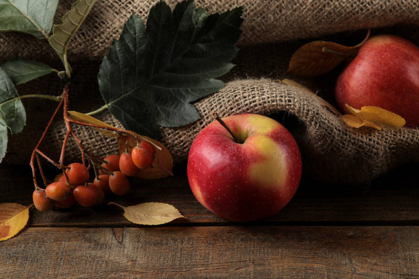 Herbstliches Arrangement mit Obstäpfeln und Birnen und gelben Herbstblättern auf einem braunen Holztisch - Foto, Bild